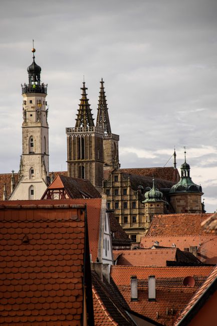 A scenic view of Gothic towers in Rothenburg framed by traditional red rooftops.