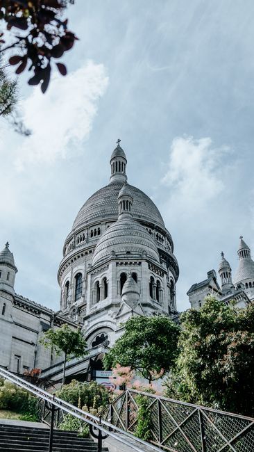 View of Sacré-Cœur Basilica in Paris with clear blue sky, showcasing its iconic architecture and lush surroundings.