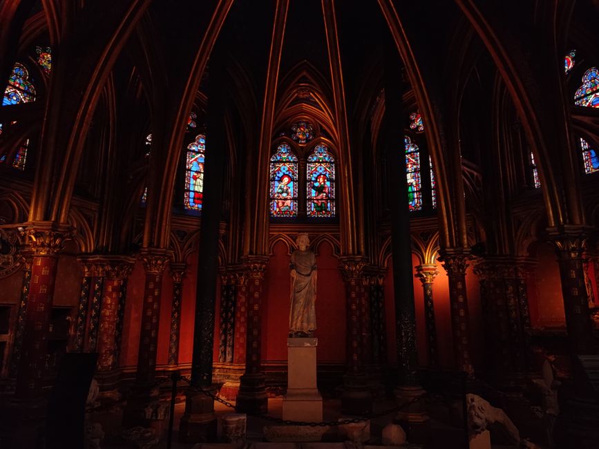 Gothic interior of Sainte-Chapelle in Paris with vibrant stained glass windows and sculptures.
