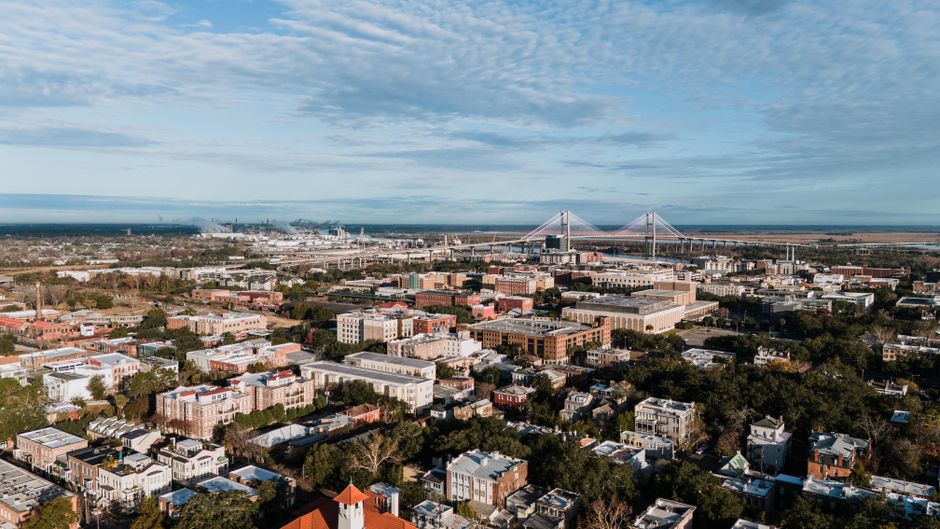 A sweeping aerial view of Savannah, GA, featuring the Talmadge Bridge and surrounding cityscape.