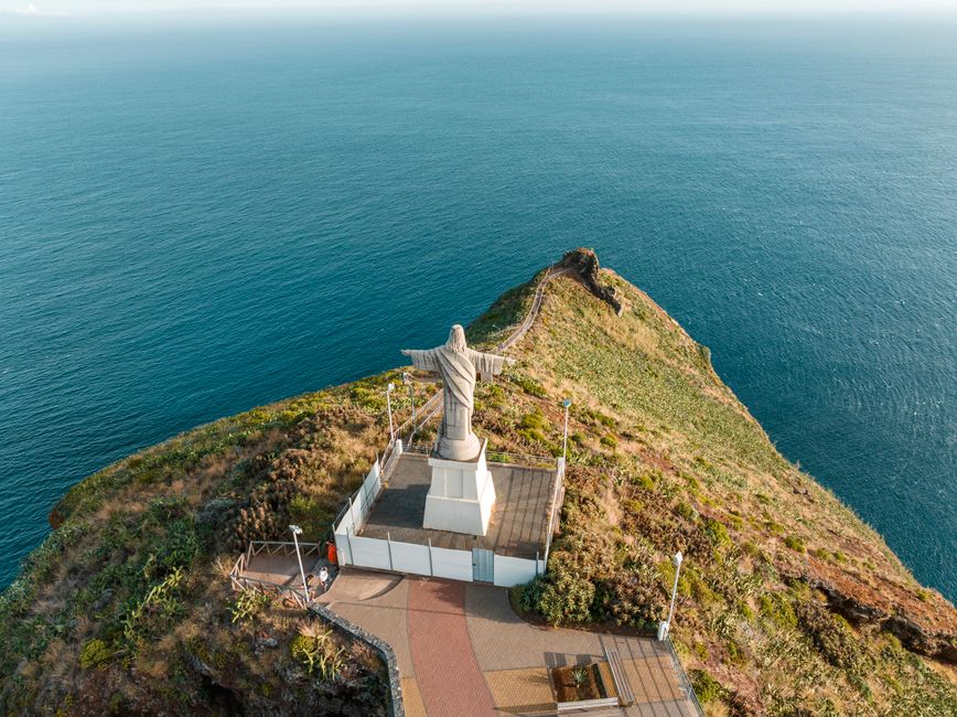 A stunning aerial photo of the Cristo Rei statue overlooking the Atlantic Ocean in Madeira, Portugal.