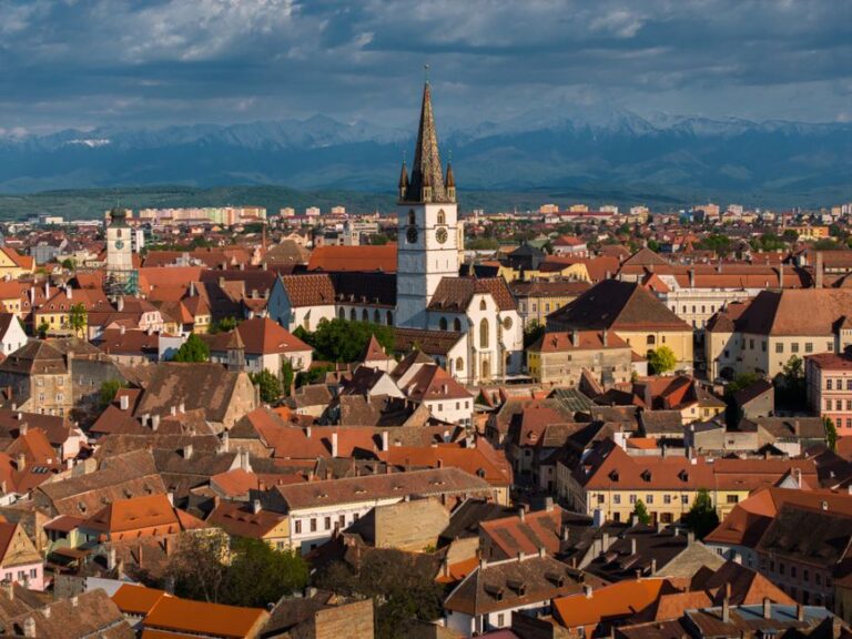 Aerial view of Sibiu, Romania showcasing historic architecture and mountainous backdrop.