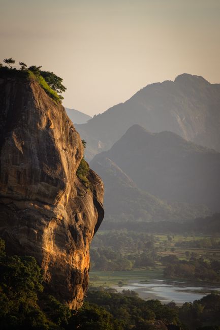 Breathtaking view of Sigiriya Rock in Sri Lanka with a mountainous backdrop at sunrise.