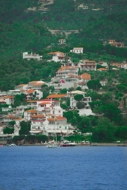 Charming town of Skiathos in Greece with vibrant houses and lush greenery overlooking the sea.