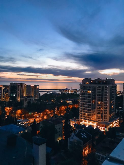 Beautiful view of Sochi skyline at sunset, capturing the vibrancy of city lights and coastal backdrop.