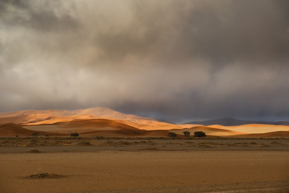 Stunning landscape of sand dunes under dramatic clouds in the Namib Desert, Namibia.