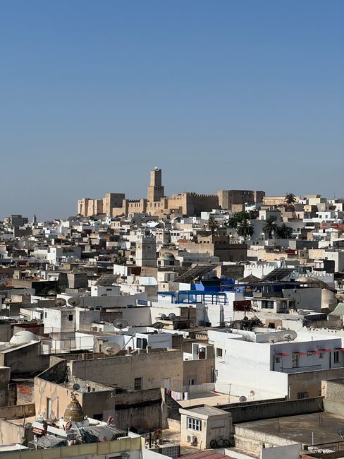 Scenic aerial view of the historic medina and fortress under a clear blue sky.