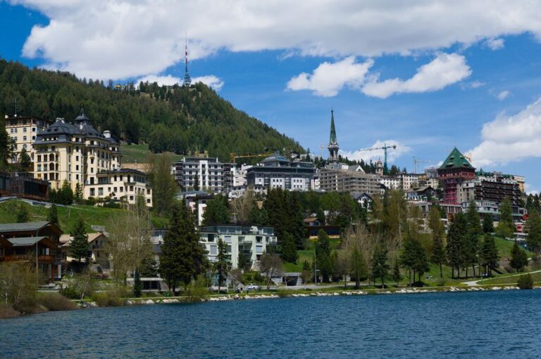 Beautiful day view of St. Moritz with its classic architecture, surrounded by mountains and a serene lake.