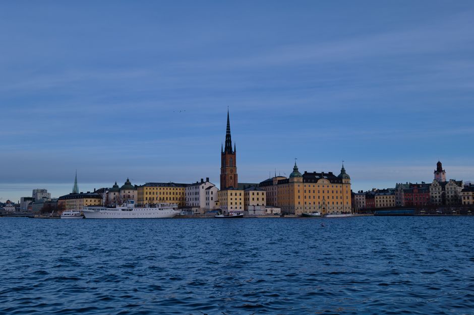 Skyline of Stockholm with historic architecture reflecting on water under a clear sky.