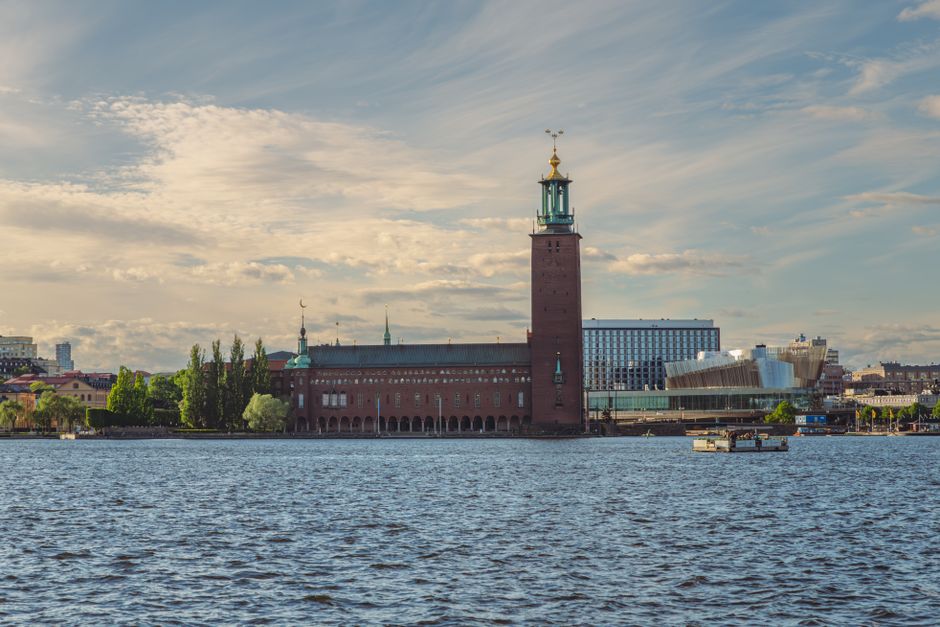 Beautiful view of Stockholm City Hall and waterfront under a cloudy sky.