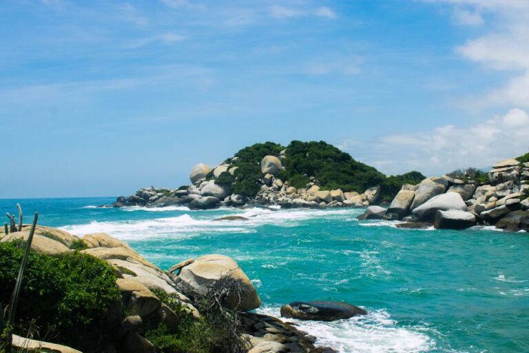 A picturesque view of Tayrona National Park with rocks and turquoise sea under a blue sky.