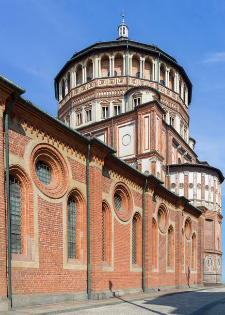 View of Santa Maria delle Grazie's red brick architecture against a clear sky.
