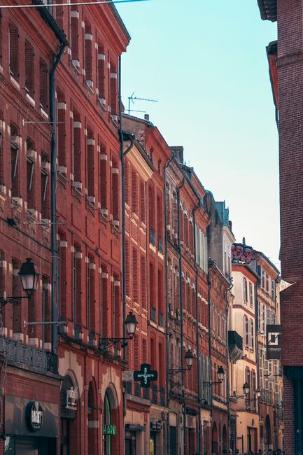 Classic view of red brick buildings on a picturesque street in Toulouse, France.