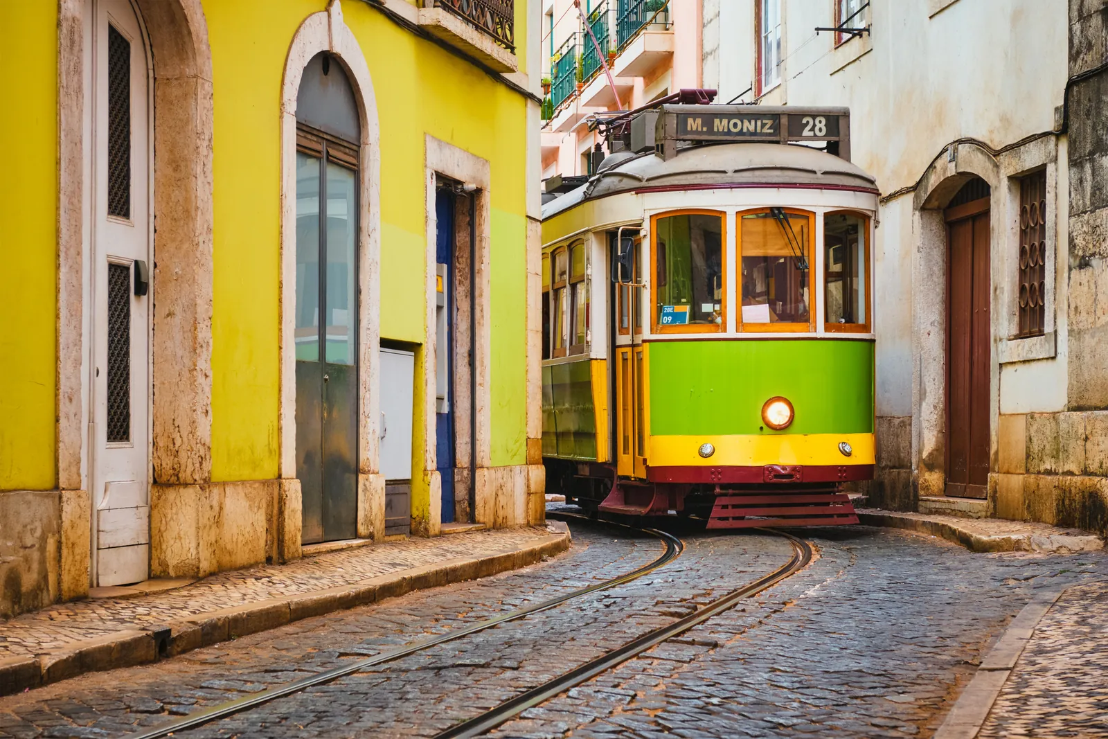 Yellow vintage tram 28 in the narrow streets of the Alfama district, Lisbon