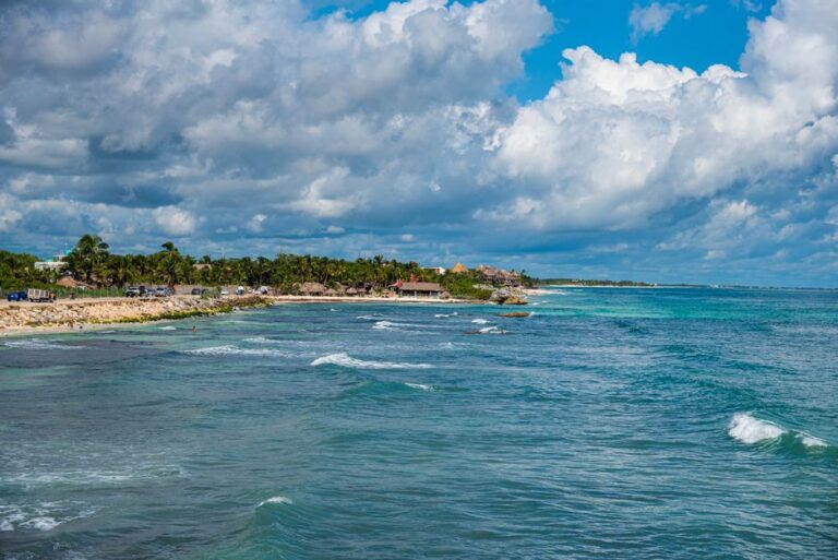 Vibrant coastal view of Tulum with turquoise waters and lush greenery under bright blue skies.