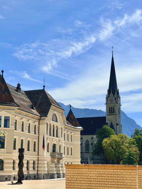 Sunlit view of Vaduz with the striking Cathedral of St. Florin set against the Alps.