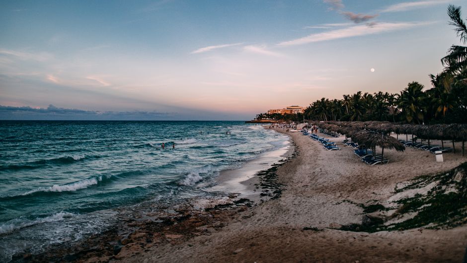 Beautiful view of Varadero beach at sunset with palm trees and calm waves.