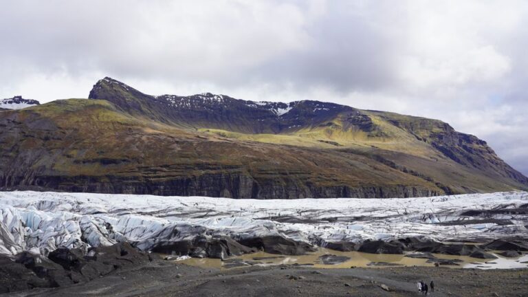 A breathtaking view of an Icelandic glacier with rugged mountains under a cloudy sky.