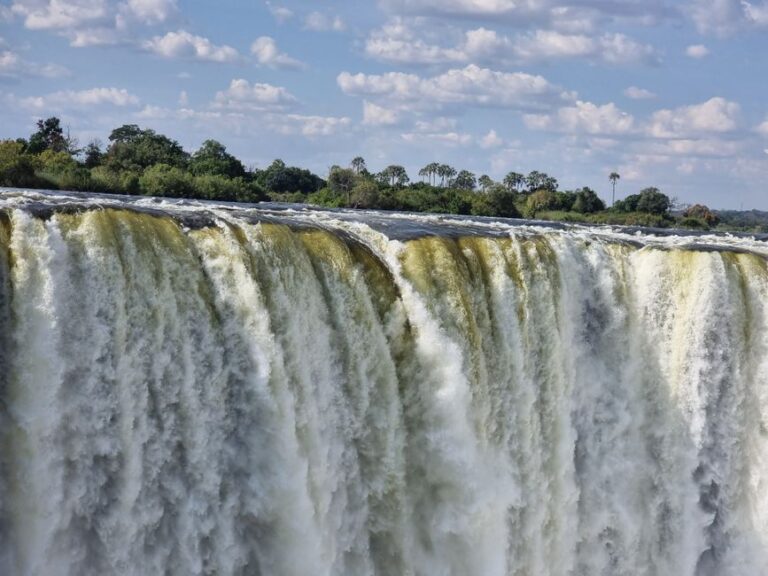 Stunning view of Victoria Falls cascading with vibrant energy, surrounded by lush greenery.