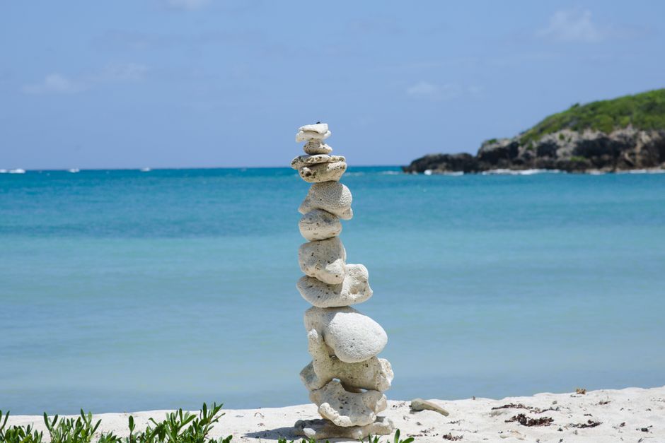 Peaceful rock stack on a sandy shore, overlooking the turquoise sea in Vieques, Puerto Rico.