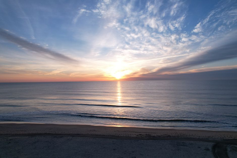 Beautiful sunrise over Virginia Beach with gentle waves and vibrant skies, perfect for relaxation themes.