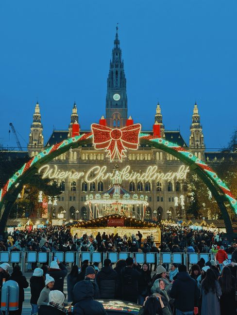 Experience the Wiener Christkindlmarkt in Vienna, Austria. A vibrant scene with festive lights and a lively crowd.