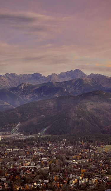 A beautiful aerial view of Zakopane cityscape with the Tatra Mountains in the background at sunrise.