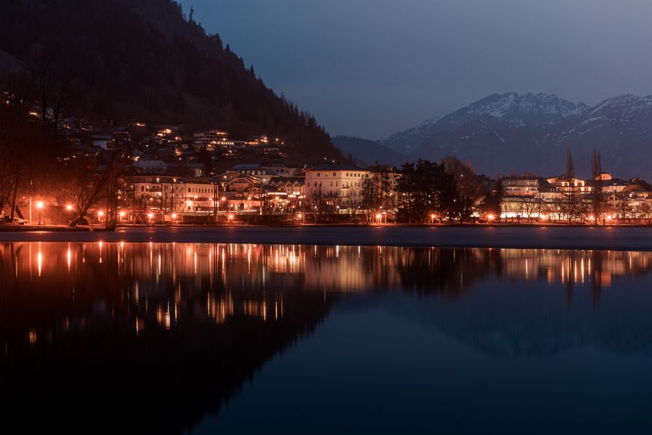 Scenic view of Zell am See town illuminated at dusk, reflecting beautifully in the calm lake waters.